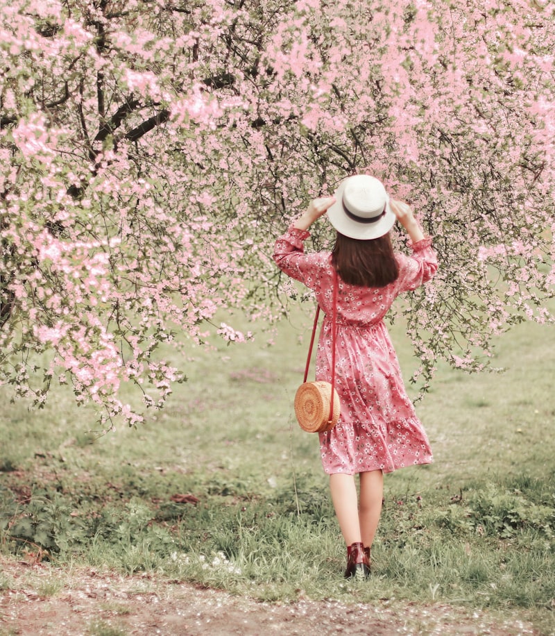 Woman in floral dress under spring blossoms - communion and confirmation outfit inspiration